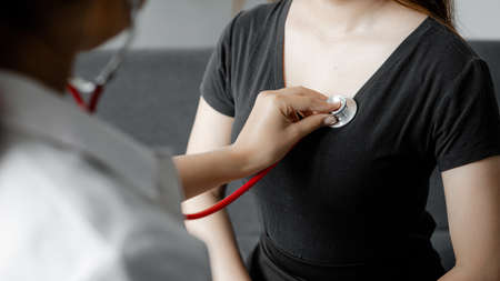 A female doctor using a stethoscope, she is examining the patient in the examination room and...