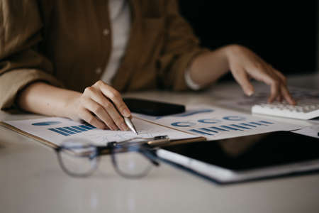 A business finance woman is reviewing a company's financial documents prepared by the Finance Department for a meeting with business partners. Concept of validating the accuracy of financial numbers.の写真素材