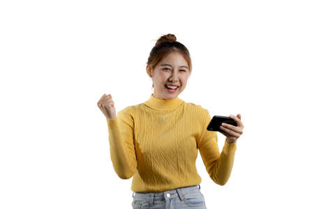 Portrait of a beautiful Asian woman in a yellow shirt playing on a smartphone. portrait concept used...
