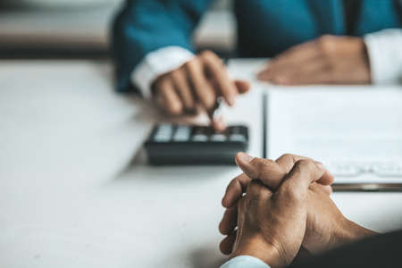 A rental company employee is calculating the cost for the customer to agree to sign a rental contract, explaining the rental terms and conditions. Home and real estate rental ideas.の写真素材