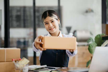 A beautiful Asian business owner opens an online store, she is checking orders from customers,...