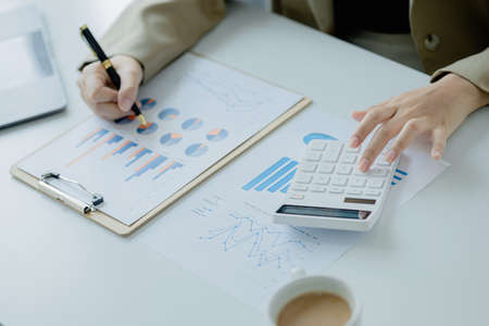 Businessman using a calculator to calculate numbers on a company's financial documents, he is analyzing historical financial data to plan how to grow the company. Financial concept.の写真素材
