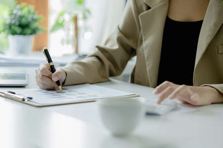 Businessman using a calculator to calculate numbers on a company's financial documents, he is analyzing historical financial data to plan how to grow the company. Financial concept.の写真素材