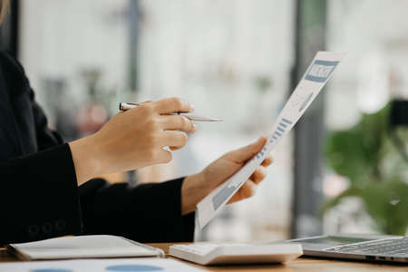 Business women are looking at the company's financial documents to analyze problems and find...