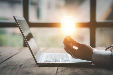 Standing man hold glowing light bulb, Creative new idea. Innovation, brainstorming, strategizing to...