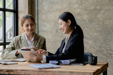 Two Asian business women are meeting to summarize the company's operating, financial, profit and loss results. Management of startup companies. Profitable management concept and growing management.の写真素材