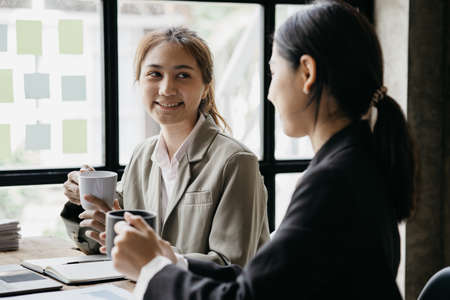 Two Asian business women are meeting to summarize the company's operating, financial, profit and...