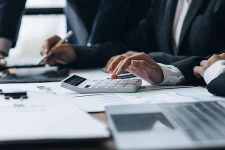 Businessman using a calculator to calculate numbers on a company's financial documents, he is analyzing historical financial data to plan how to grow the company. Financial concept.の写真素材