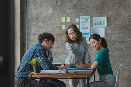 A startup executive is meeting with a new generation of employees to plan and discuss, she is an experienced senior executive with a modern mindset. Management concept of startup company.の写真素材