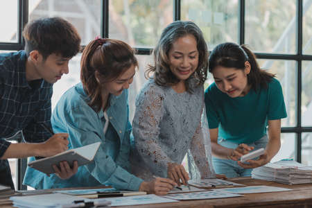 A startup executive is meeting with a new generation of employees to plan and discuss, she is an experienced senior executive with a modern mindset. Management concept of startup company.の写真素材