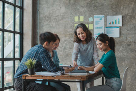 A startup executive is meeting with a new generation of employees to plan and discuss, she is an experienced senior executive with a modern mindset. Management concept of startup company.の写真素材
