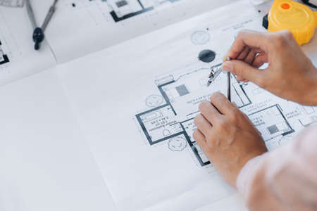 A building and house architect is reviewing and revising the house designs of a large housing project, he draws roundabouts on the house plans. Home and interior design ideas by architect engineers.の写真素材