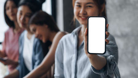 Asian woman holding white blank screen phone standing forward, smartphone blank screen for advertisement, smartphone application. Photo collage ideas for advertisements. copy space.の写真素材