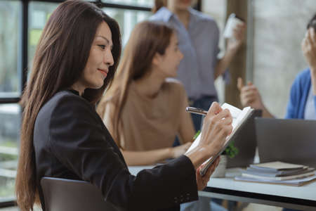 Asian teenage women sit in a startup company meeting room, young generation co-found and develop a plan to grow and differentiate a startup company. Startup company development by new generation.の写真素材