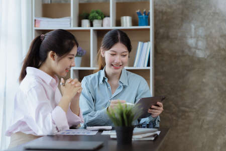 Beautiful Asian woman chatting with colleague in company office, businesswoman operating company...
