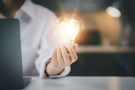 Standing woman holding glowing lamp, Creative new idea. Innovation, brainstorming, strategizing to make the business grow and be profitable. Concept execution, strategy planning and profit management.の写真素材