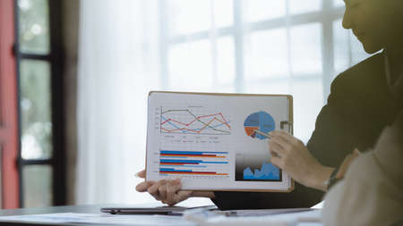 Atmosphere in the office of a startup company, two female employees are discussing, brainstorming ideas to working on summaries and marketing plans to increase sales and prepare reports to managers.の写真素材