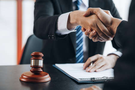 Lawyers shake hands with clients who come to testify in the case of embezzlement from business partners who jointly invest in the business. The concept of hiring a lawyer for legal proceedings.の写真素材