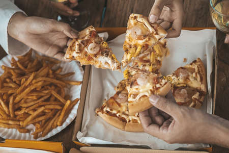 Hands people picking up pizza on a tray to eat, startup company parties, New Year's parties, company annual gatherings, alcoholic beverages. Company employee party catering ideas, pizza celebrations.の写真素材