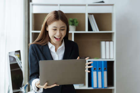 Asian businesswoman looking at laptop screen and remote video call with startup partner, she talks to her friend through program on laptop. Concept of using communication technology.の写真素材
