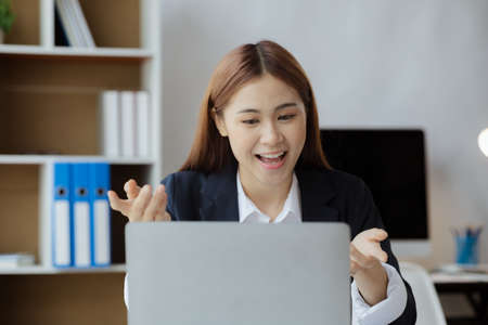 Asian businesswoman looking at laptop screen and remote video call with startup partner, she talks to her friend through program on laptop. Concept of using communication technology.の写真素材