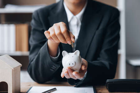 Individuals are putting money into the piggy bank, real estate trading, condo houses, financial planning for housing. Money saving ideas to buy housing.の写真素材