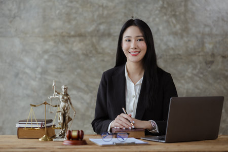 An Asian female lawyer is at her law firm, she is a lawyer advising on various litigation cases. To clients who are in trouble in the legal way. Concept of female lawyer and justice of the law.の写真素材