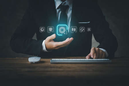 Businessman wearing suit with keyboard and mouse, hologram setting icon on electronic instrument, modern technology concept. analytics and development solutions modern business Innovation of new ideasの写真素材