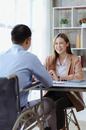 Man sits in a wheelchair and brainstorms with colleagues, conducts business, recruits people with disabilities to work, works with in-house teams and has people with disabilities as part of the team.の写真素材