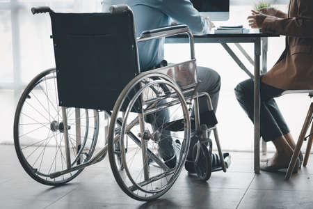 Man sits in a wheelchair and brainstorms with colleagues, conducts business, recruits people with...