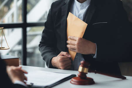 Individuals are giving bribes to officials in order to commit corruption in lawsuits, illegal actions by law enforcement by paying bribes to officials are illegal and unlawful. Fraud concept.の写真素材