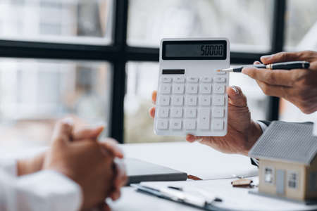 Rental company employee is discussing the details before the customer agrees to sign a rental contract, explaining the details and the terms and conditions of the rental. Real estate rental ideas.の写真素材