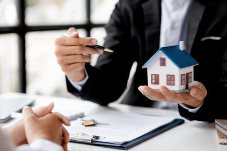 Rental company employee is discussing the details before the customer agrees to sign a rental contract, explaining the details and the terms and conditions of the rental. Real estate rental ideas.の写真素材