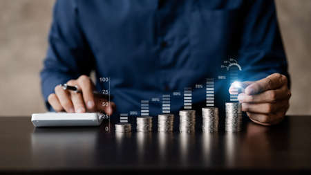 Business man putting a coin on a pile of coins. Placing coins in a row from low to high is...