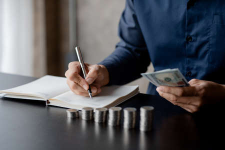 A man counting her salary to separate expenses, he keeps a monthly account for savings and investment plans, savings and investment ideas to make money grow for wealth.の写真素材
