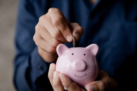 A businessman holding a coin in a piggy bank. Placing coins in a row from low to high is comparable...