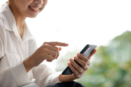Asian woman using mobile phone, she surfs internet and social media on smartphone, chatting on app with friends. The concept of using technology in communication and the use of the Internet.の写真素材