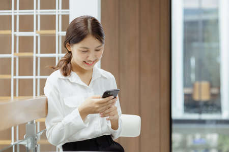 Asian woman using mobile phone, she surfs internet and social media on smartphone, chatting on app...