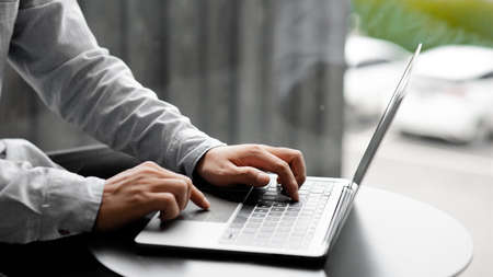 Businessman typing on a laptop keyboard, he is filling out his credit card information to pay for an...