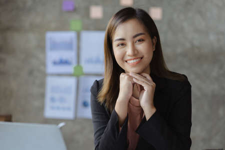 A beautiful Asian businesswoman sitting in her private office, she is checking company financial documents, she is a female executive of a startup company. Concept of financial management.の写真素材