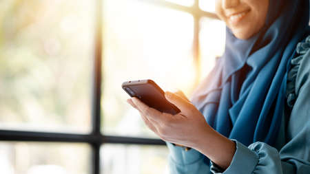 Asian women in hijab are using the mobile phone, administration and operations from the young, smart...