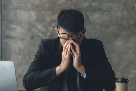 A business man tired and stressed from hard work, he runs a startup company that is facing financial problems and needs to find a solution to keep the company running. Company management concept.の写真素材