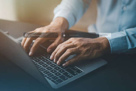 An individual is typing on a keyboard laptop showing a hologram interface to a member login, a...