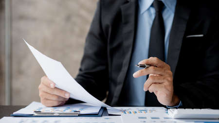 Business men are looking at the company's financial documents to analyze problems and find solutions before bringing the information to a meeting with a partner. Financial concept.の写真素材