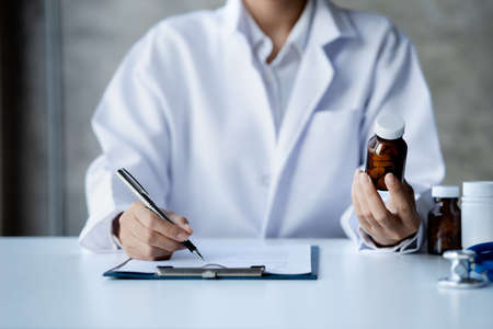 Physicians view diagnostic documents and hold medications in hospital rooms, treating diseases from specialists and providing targeted treatment. Concepts of medical treatment and specialists.の写真素材