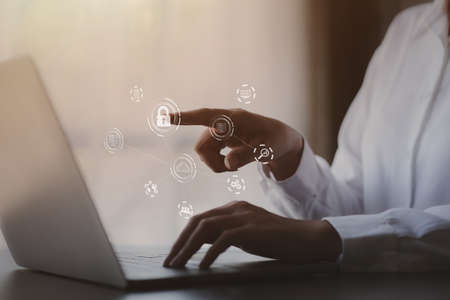 An individual is typing on a keyboard laptop showing a hologram interface to a member login, a...