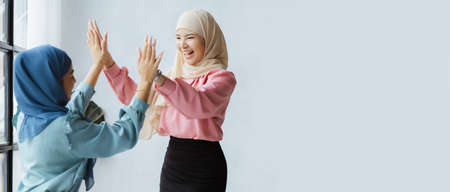 Two hijab Asian women clapping hands together as congratulation after successfully working together. run by a young, talented woman. Management concept runs the company female leaders to grow company.の写真素材