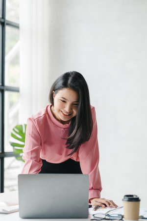 Asian woman working in a startup company, she is working in the office. run by a young, talented...