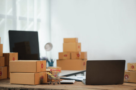 Desks e-commerce stores on websites and sales applications, desks pack products into parcel boxes according to customer orders through online channels. Concept of online selling and product packaging.の写真素材