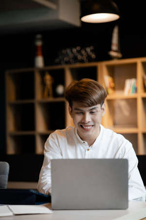 A man sits in the office of a startup company, he is an employee working in the marketing...